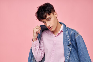 portrait of a young man in youth stylish clothes denim jacket posing pink background unaltered