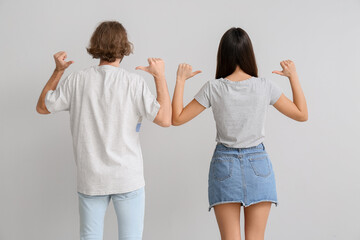 Wall Mural - Young couple in stylish t-shirts on light background, back view