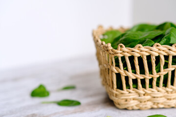 Green juicy fresh raw spinach in a wicker basket on a wooden table. Organic superfood. Nutrition and treatment. Vitamins and minerals. Healing. Vegan food. Immune system support. Health care, wellness