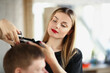 © H_Ko - A beautiful woman cuts a man's hair with scissors, close-up