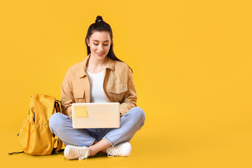 Wall Mural - Portrait of beautiful female student with laptop on color background