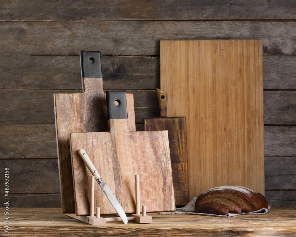 Cutting boards, knife and bread on wooden background