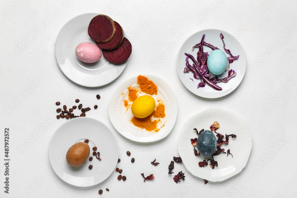 Plates with homemade dyed Easter eggs on white background