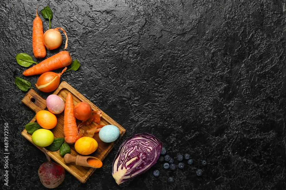 Wooden board with Easter eggs and natural dyes on dark background