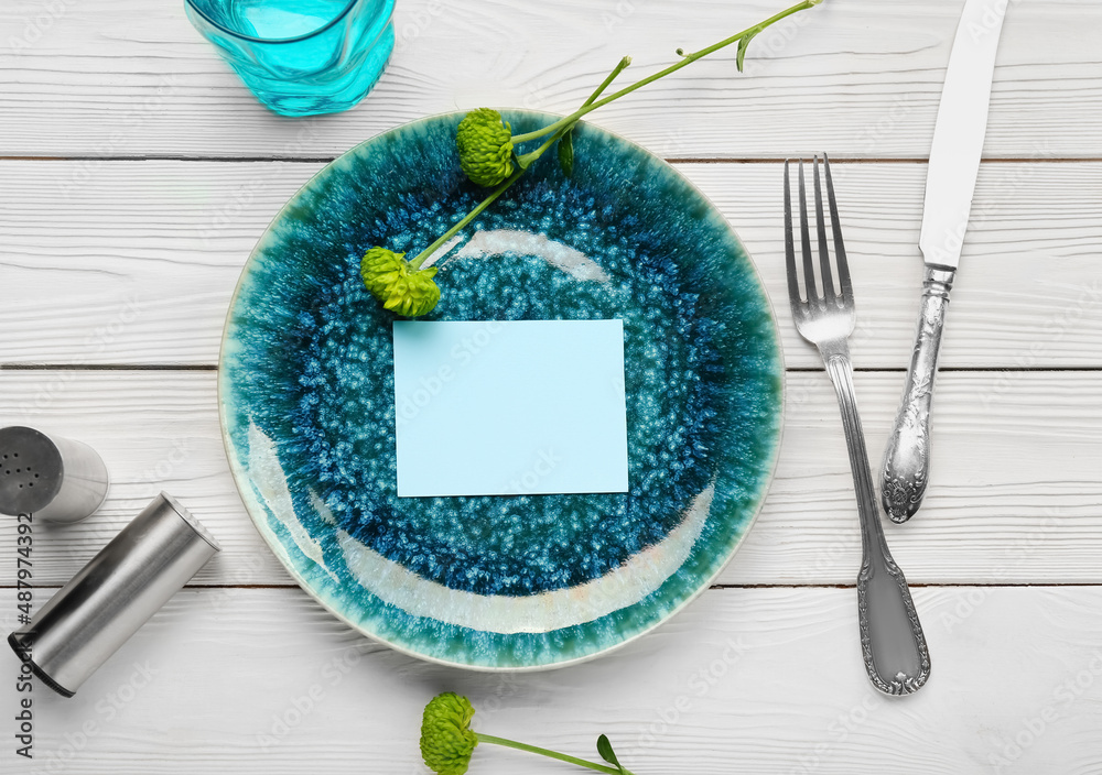 Stylish table setting with blank card and flowers on white wooden background