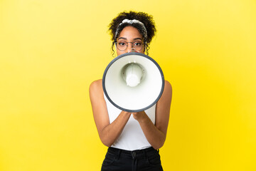 Wall Mural - Young african american woman isolated on yellow background shouting through a megaphone to announce something