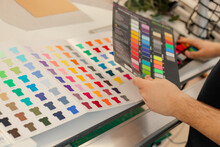Cropped Man Hands Choosing Samples Catalog Palette Rack Color Advertising T-shirts Palette Film Membrane. Close Up