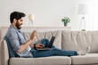 © Prostock-studio - Online communication concept. Arab man making virtual video call on laptop, talking and waving hand at webcam