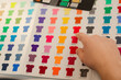 Cropped man hand choosing samples templates multicolor advertising T-shirts palette film membrane. Textile production