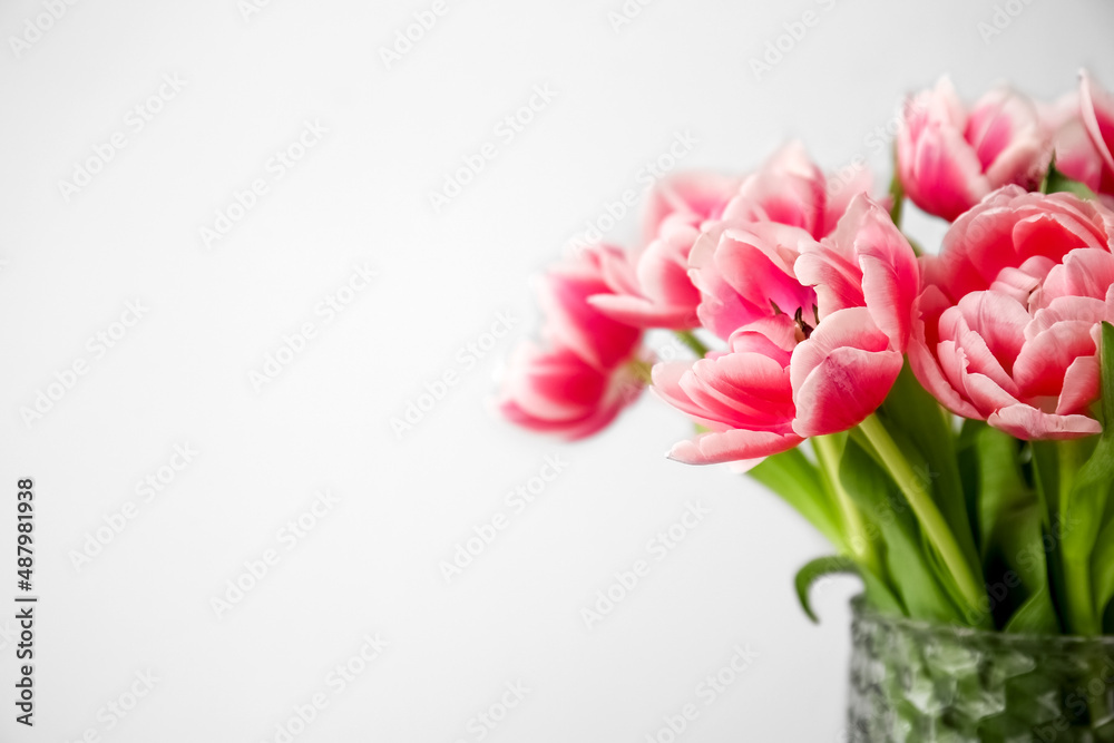 Vase with tulips on grey background, closeup
