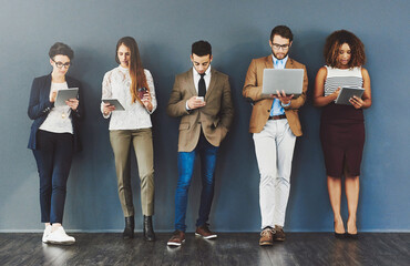 Poster - Wireless entertainment for the wait. Studio shot of a group of businesspeople using wireless technology while waiting in line against a gray background.