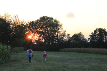 Wall Mural - The two kids running in the field at sunset