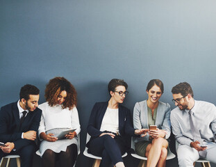 Poster - Nothing brings people together like technology. Studio shot of a group of businesspeople using wireless technology while waiting in line against a gray background.