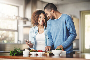 Poster - I found the perfect recipe. Shot of a happy young couple using a digital tablet while preparing a healthy meal together at home.