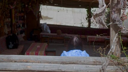 rear view of woman and girl sitting on bench in rural area. heads of woman and daughter sitting toge