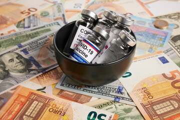 Wall Mural - Covid vaccines in ceramic bowl - photo on money bank notes. Coronavirus vaccine vials in black ceramic is placed on money bank notes. Euro and dollar banknotes as background for Covid-19 inoculation.