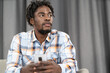 © Svyatoslav Lypynskyy - Thoughtful African American man use smartphone checking social media or updating information. Portrait of young man holding smartphone sitting on the sofa. Social media concept