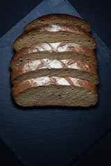 Wall Mural - Bread on a black background. Sliced fresh homemade bread in a dark dish. Traditional food