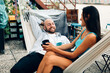 © Carlo - friends colleagues couple relaxing cuddling in a hammock holding a cup of tea or coffee