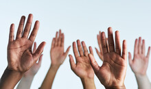 Raise Your Hands As One. Shot Of A Group Of Hands Reaching Up Against A White Background.