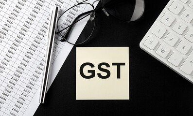 Poster - Concept GST message on sticker with glasses,chart and calculator on the black background