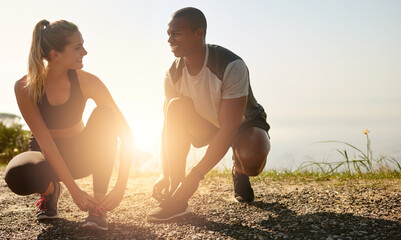 Canvas Print - Grab your workout buddy and go. Shot of a fit young couple tying their shoelaces before a run outdoors.