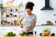 © kucherav - Healthy diet eating. African American young female preparing salad in home kitchen. Beautiful woman cooking healthy food, breakfast or dinner