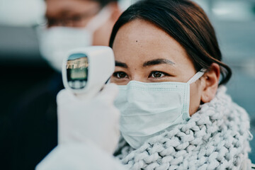 Canvas Print - The quicker way to get results. Shot of a young woman getting her temperature taken with an infrared thermometer by a healthcare worker during an outbreak.