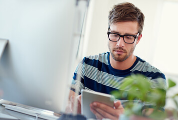 Wall Mural - This site needs some work. Shot of a casually-dressed young man using a digital tablet at his desk.