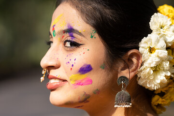 Wall Mural - Holi festival of color, young beautiful girl or woman or lady playing holi with dry organic color or colour or gulal or abeer or Holi powder