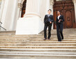 © DW labs Incorporated - A well dressed man and woman smiling as they as they walk down steps of a courthouse  building. Could be business or legal professionals.
