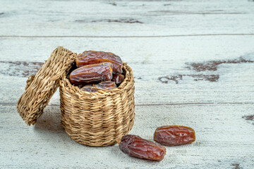 Wall Mural - close up picture of dates palm fruit in cup on wooden table background. Dates palm fruit dry is snack healthy.