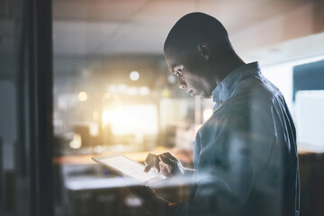 Poster - Anything is doable with dedication. Cropped shot of a handsome young businessman using a digital tablet during a late night in a modern office.