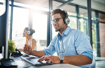 Sticker - Theyve got the answers youre looking for. Cropped shot of a handsome young man working in a call center with a female colleague in the background.