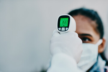 Canvas Print - Cutting edge tech to help curb the spread. Shot of a young woman getting her temperature taken with an infrared thermometer by a healthcare worker during an outbreak.