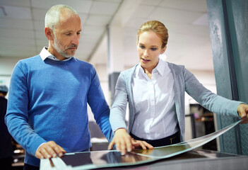 Aufkleber - Assuring quality throughout the process. Two publishers assessing the quality of printed work in a factory.