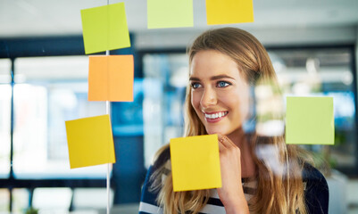 Poster - Creativity is a process. Shot of a young woman having a brainstorming session with sticky notes at work.