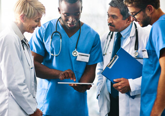 Sticker - Making patient care smarter with smart technology. Shot of a team of doctors using a digital tablet together in a hospital.