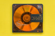 Orange recordable mini disc from the 1990's. Close up above view with yellow background.