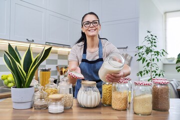 Wall Mural - Smiling woman in the kitchen with jars of stored food.