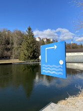 A Vertical Closeup Of The Blue Sign On The Bank Of The River.