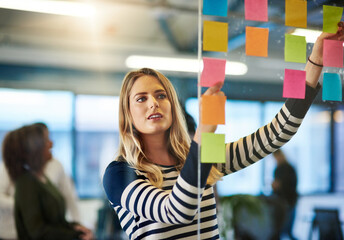 Aufkleber - Attaining success with a well mapped out plan. Shot of a young woman having a brainstorming session with sticky notes at work.