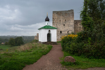 Wall Mural - View of the Chapel of the Korsunskaya Icon of the Mother of God against the background of the Talavskaya Tower and the wall of the Izborsk fortress on a summer day, Izborsk, Pskov region