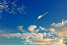 Feather Shaped Cloud In The Blue Sky At Sunset. Beautiful Puffy White Clouds.  Weather Natural Background, Wallpaper.