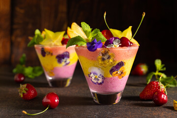 Wall Mural - Delicious layered berry and fruit smoothie with edible flowers. Healthy dessert. Clean eating.