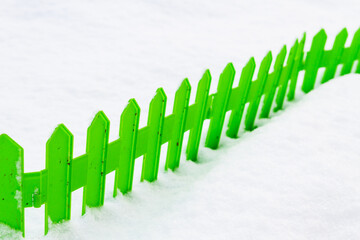 Wall Mural - Green plastic fence in the snow in the garden in winter