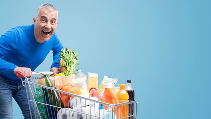 Excited man pushing a full trolley