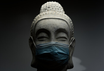 Poster - A closeup shot of Buddha statue with face mask