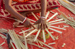 Hands of a working Indian woman in closeup weaving a basket with bamboo straws
