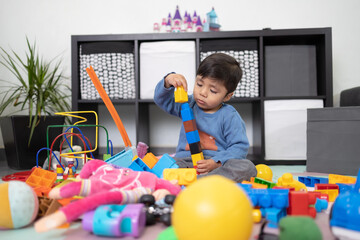 Wall Mural - two years old mexican baby boy playing with didactic toy on messy living room